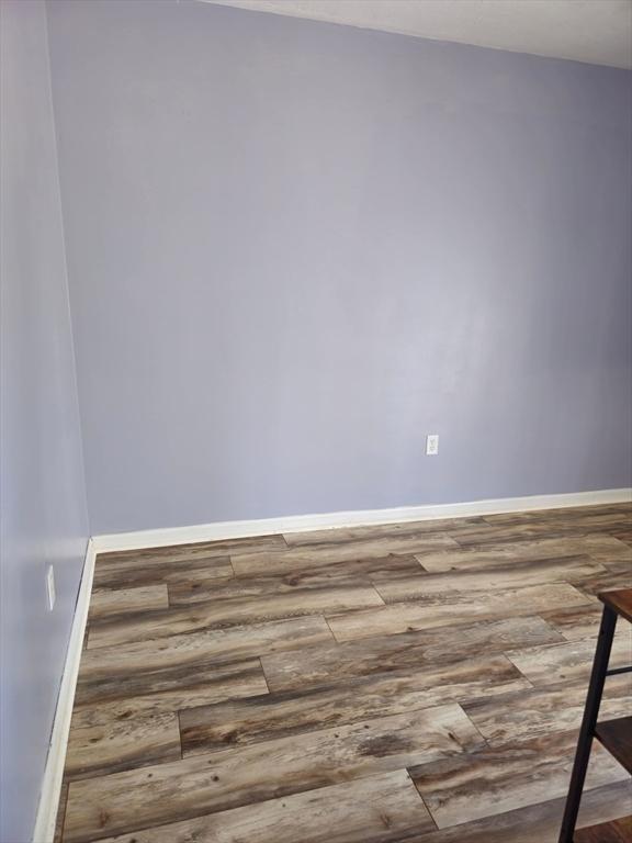 spare room featuring baseboards and wood-type flooring