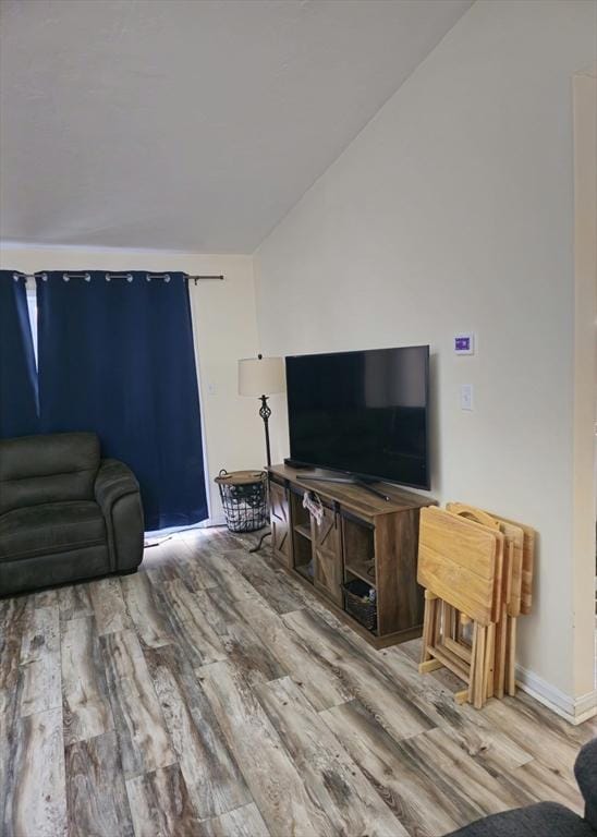 living area with wood finished floors and vaulted ceiling