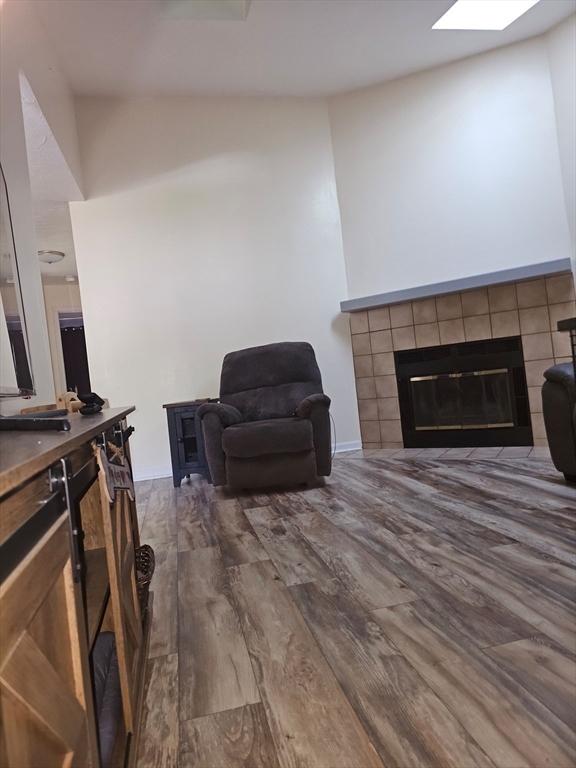 living room with a fireplace, dark wood finished floors, and a skylight