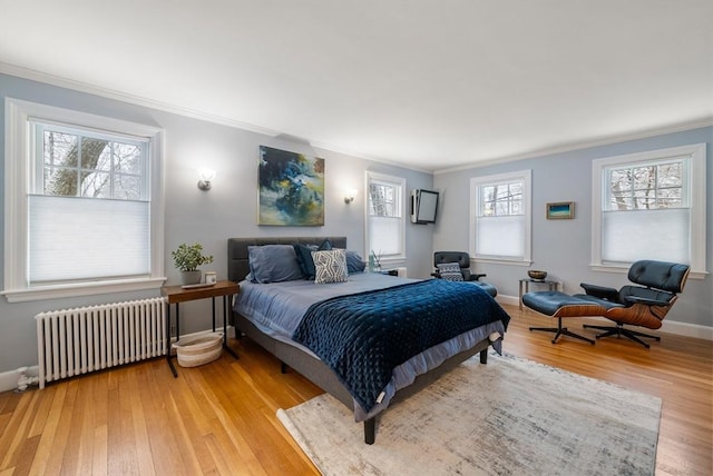 bedroom with light hardwood / wood-style floors, radiator heating unit, and crown molding