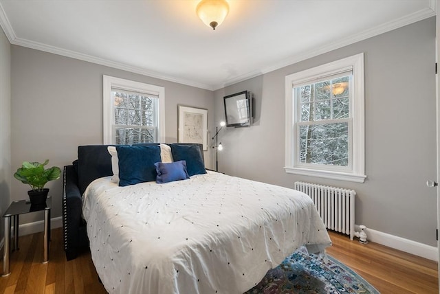 bedroom featuring multiple windows, crown molding, radiator heating unit, and wood-type flooring