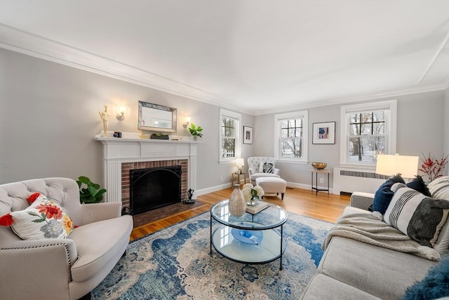 living room with ornamental molding, radiator heating unit, hardwood / wood-style floors, and a brick fireplace