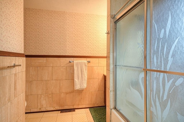 bathroom featuring bath / shower combo with glass door, tile walls, and tile patterned floors