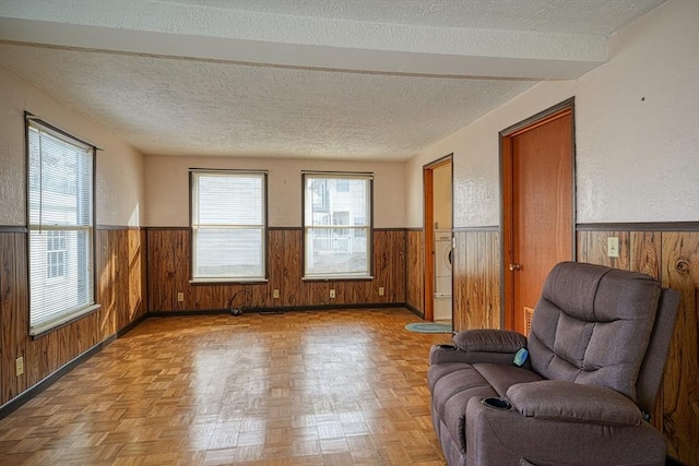 unfurnished room featuring a textured ceiling, light parquet floors, and wooden walls