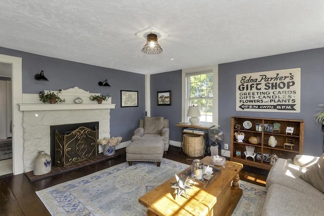 685 Main St, Wilbraham, MA 01095 - living room featuring hardwood / wood-style floors, a stone fireplace, a textured ceiling, and baseboards
