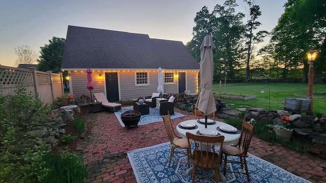685 Main St, Wilbraham, MA 01095 - back of house at dusk featuring a patio, outdoor dining area, a shingled roof, and an outbuilding