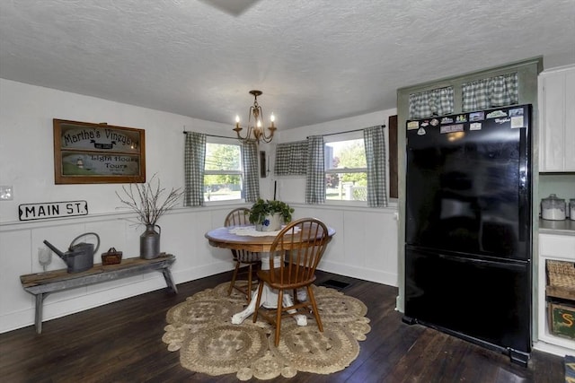 685 Main St, Wilbraham, MA 01095 - dining space featuring a chandelier, wood-type flooring, a textured ceiling, a decorative wall, and a wainscoted wall