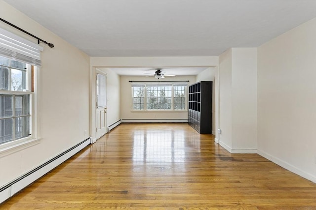 empty room with ceiling fan, light hardwood / wood-style flooring, and a baseboard heating unit