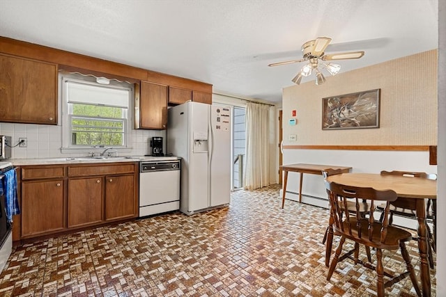 kitchen featuring white appliances, a sink, light countertops, brown cabinetry, and decorative backsplash