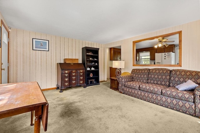 carpeted living area with wallpapered walls and a ceiling fan