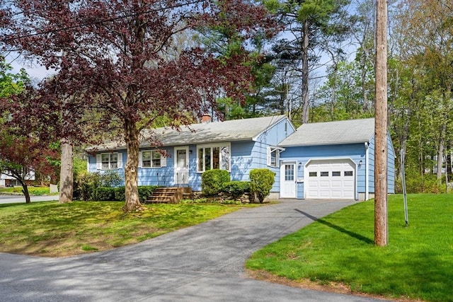 view of front of house with an attached garage, asphalt driveway, a front lawn, and a chimney