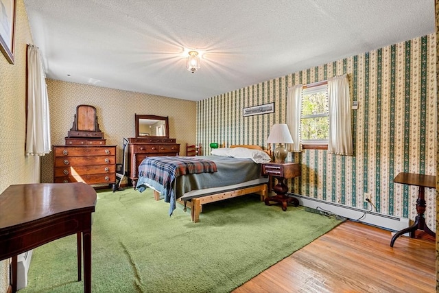bedroom featuring wallpapered walls, wood finished floors, baseboard heating, and a textured ceiling