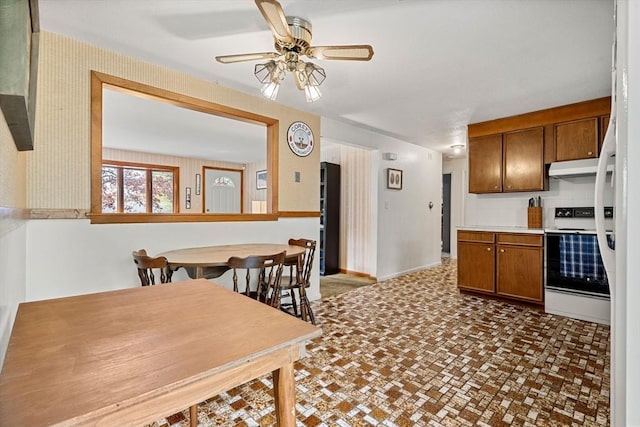 kitchen featuring electric range, ceiling fan, under cabinet range hood, and brown cabinets