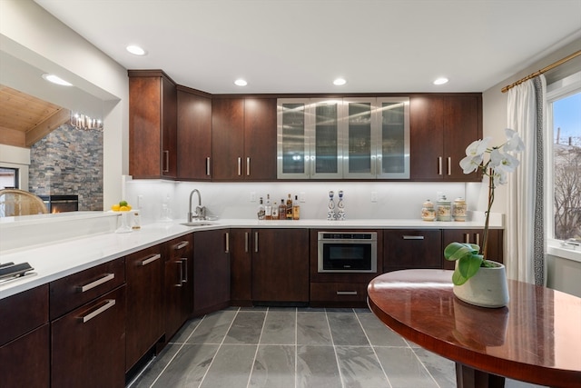 kitchen with a fireplace, dark brown cabinetry, oven, and dark tile flooring