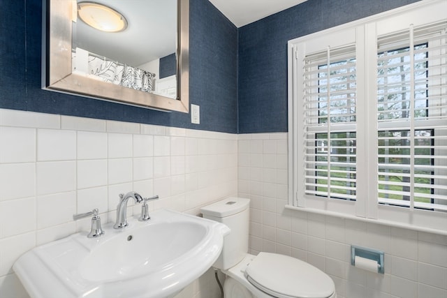 bathroom with sink, plenty of natural light, tile walls, and toilet