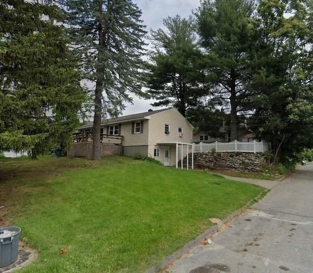 exterior space featuring a front lawn and a wooden deck