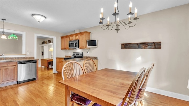 dining space with light wood-type flooring, sink, and a chandelier