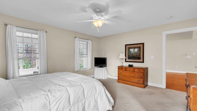 bedroom with ceiling fan, multiple windows, and light carpet