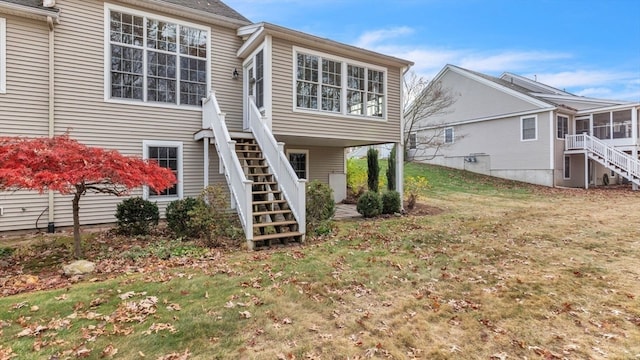 back of property with a lawn and a sunroom