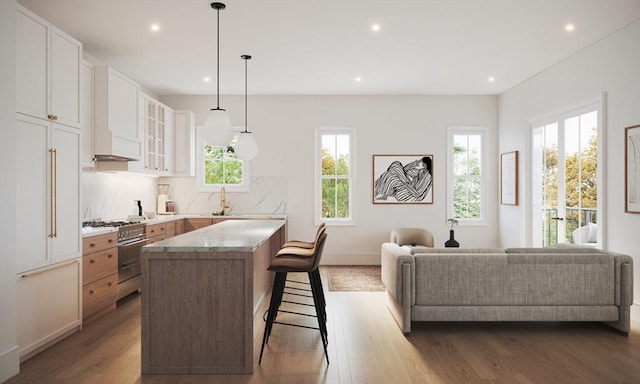 kitchen featuring light stone countertops, hanging light fixtures, a kitchen island, white cabinets, and high end range