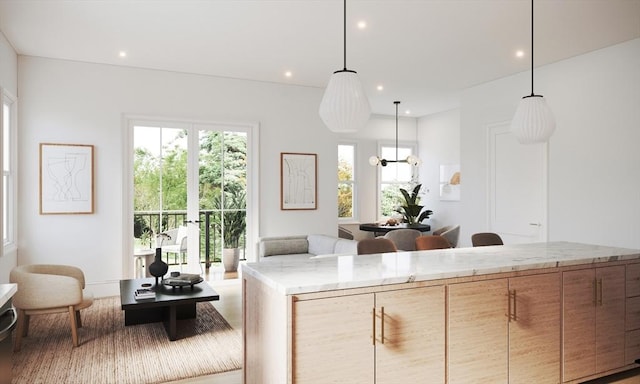 kitchen with decorative light fixtures, light stone countertops, and light brown cabinetry