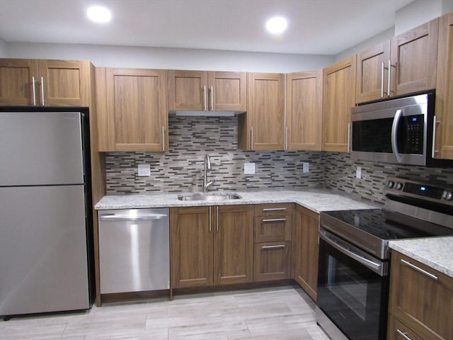 kitchen featuring sink, backsplash, stainless steel appliances, and light stone countertops