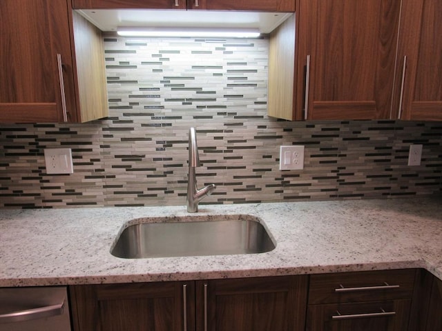 kitchen featuring light stone counters, sink, tasteful backsplash, and dishwasher