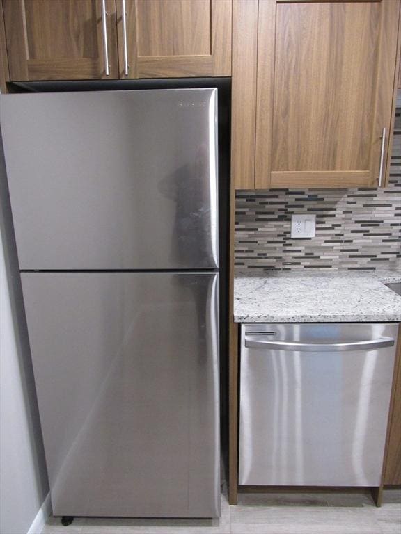 kitchen with light stone counters, decorative backsplash, and appliances with stainless steel finishes