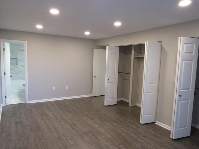 unfurnished bedroom with connected bathroom and dark wood-type flooring