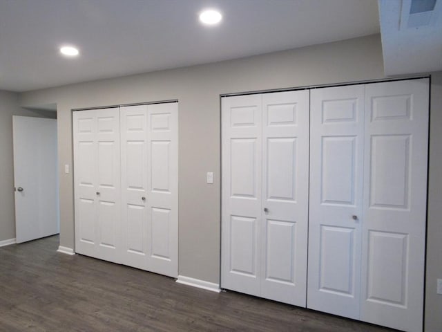 unfurnished bedroom with multiple closets and dark wood-type flooring