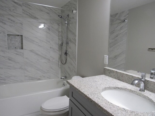 full bathroom featuring tiled shower / bath combo, vanity, and toilet