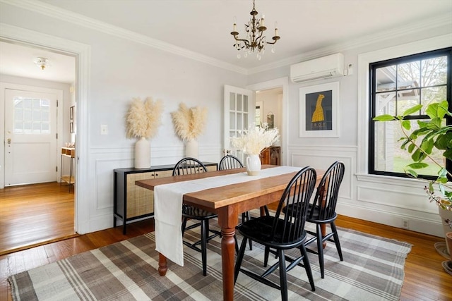 dining space featuring wood finished floors, plenty of natural light, a wall unit AC, and an inviting chandelier