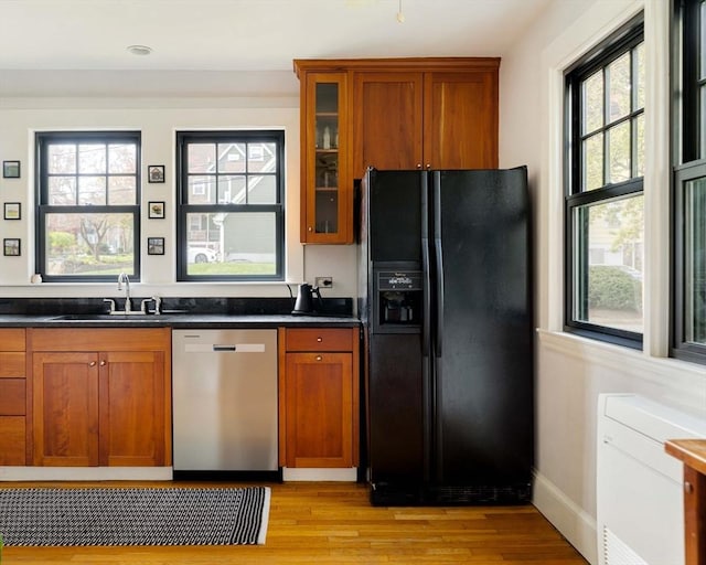kitchen with stainless steel dishwasher, dark countertops, black refrigerator with ice dispenser, and brown cabinetry