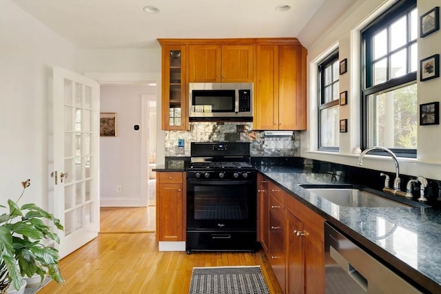 kitchen featuring a sink, dishwasher, dark stone counters, black range with gas cooktop, and stainless steel microwave