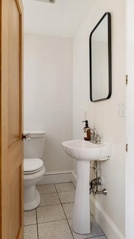 half bath featuring toilet and baseboards