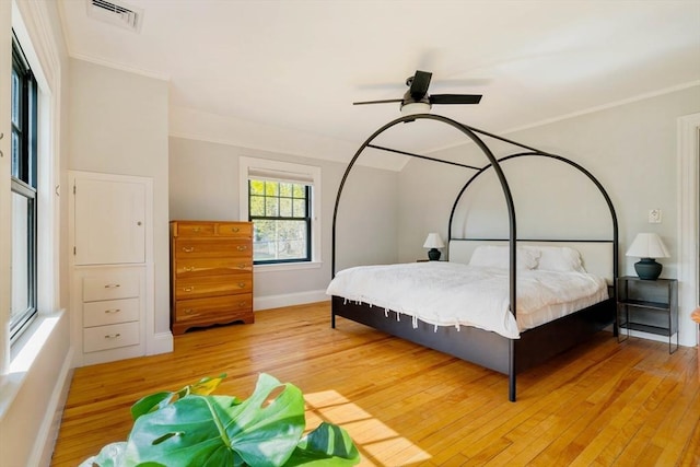 bedroom featuring visible vents, ornamental molding, baseboards, and light wood-style floors