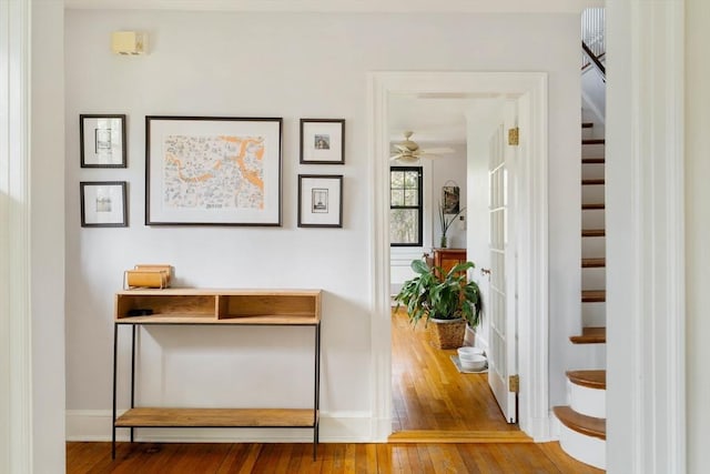 hallway with baseboards, stairs, and hardwood / wood-style flooring