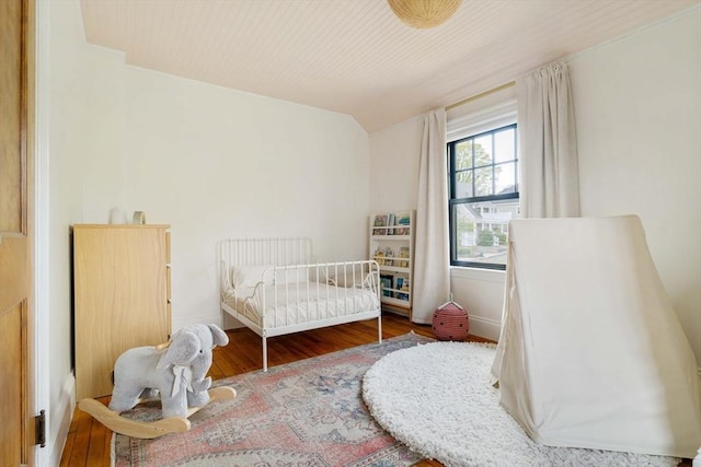 bedroom with baseboards, wood finished floors, and lofted ceiling