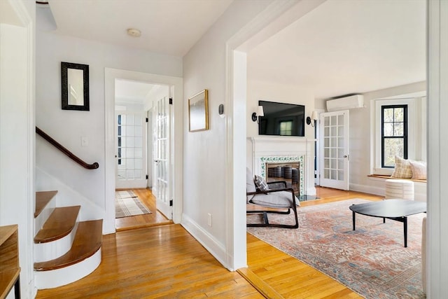 hall with baseboards, a wall mounted air conditioner, and wood finished floors