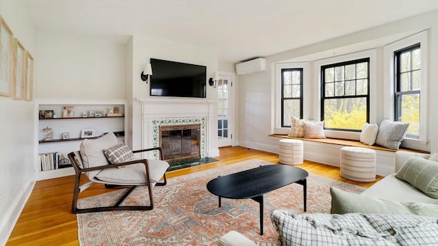living room featuring a fireplace with flush hearth, plenty of natural light, a wall mounted air conditioner, and wood finished floors