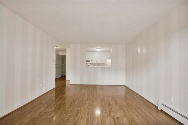 205 Independence Ave Unit 223, Quincy, MA 02169 - unfurnished living room with baseboard heating, wallpapered walls, wood finished floors, and baseboards