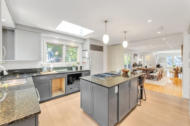 kitchen featuring a sink, stainless steel gas stovetop, gray cabinetry, a skylight, and recessed lighting