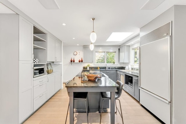 kitchen featuring open shelves, built in fridge, a sink, gray cabinetry, and light wood finished floors