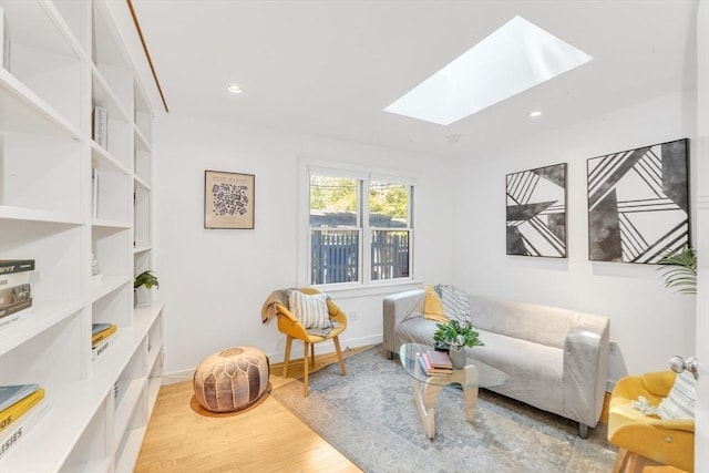 sitting room with a skylight, light wood-style flooring, recessed lighting, and baseboards
