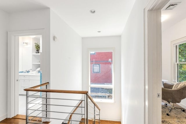 corridor with an upstairs landing, baseboards, and wood finished floors