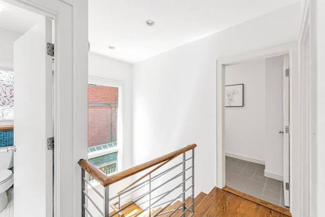 hallway with an upstairs landing and wood finished floors