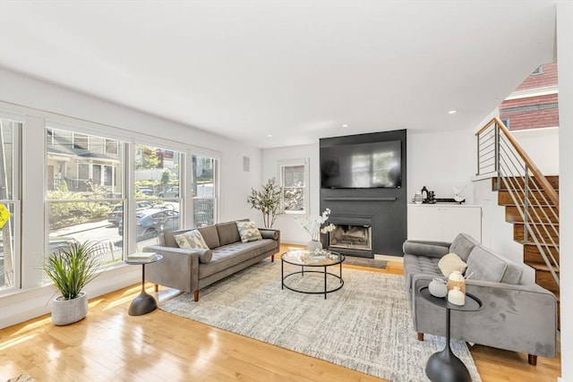 living room featuring a fireplace, wood finished floors, and stairway