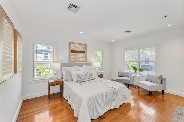 bedroom with multiple windows, light wood-style floors, baseboards, and recessed lighting