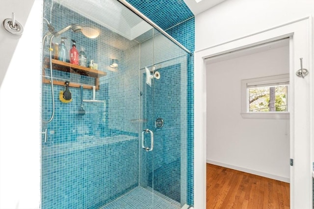 bathroom with a stall shower, wood finished floors, and baseboards
