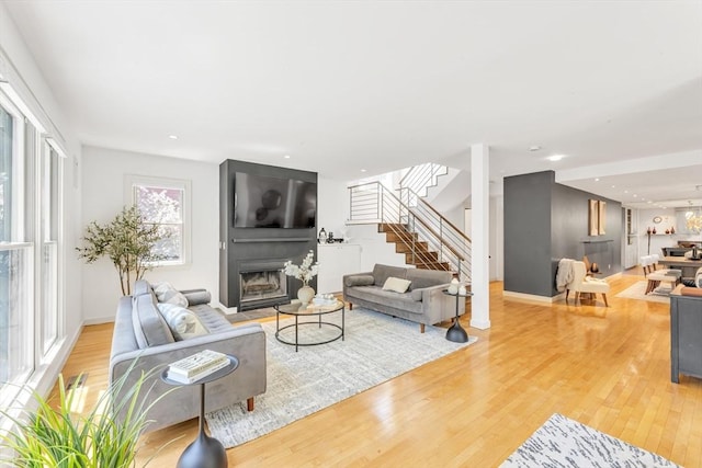 living area featuring stairs, a large fireplace, wood finished floors, and recessed lighting